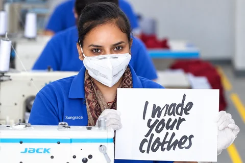 Sungrace garment worker holding an I made your clothes sign; photograph retouched for presentation