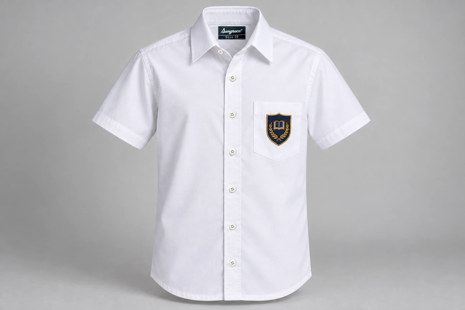 Half-Sleeve School Shirts — white with navy and gold sample shield crest. front product photograph. Illustrative catalogue concept.