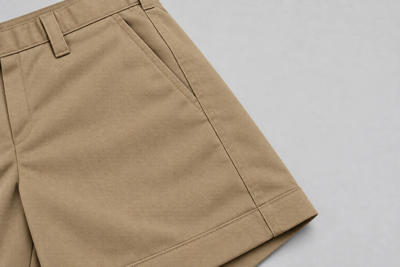 School Shorts — Khaki tailored pocket and hem. macro pocket and hem construction detail photograph. Illustrative catalogue concept.