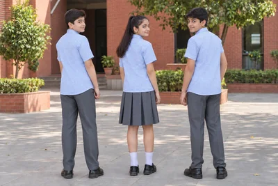 Half-Sleeve School Shirts — pale-blue checked shirts with grey bottoms; two boys and one girl. full-length rear three-quarter group location photograph. Illustrative catalogue concept.