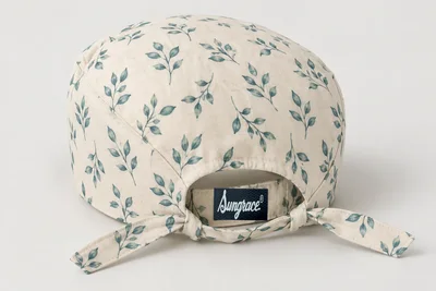 Scrub Caps — Cream woven scrub cap with small original muted teal leaf print and tie back. product rear three-quarter. Illustrative catalogue concept.